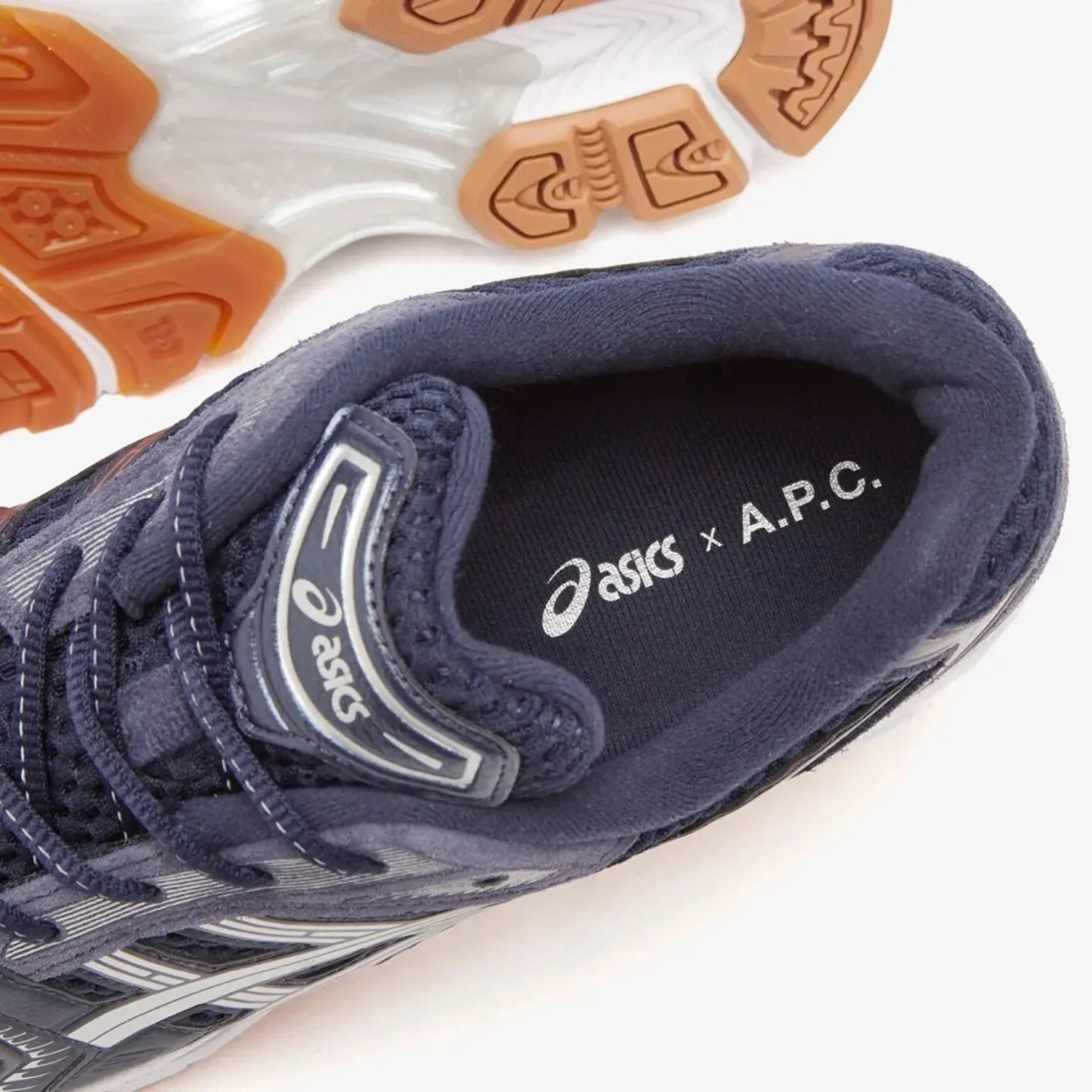Sneaker vastgehouden in daglicht – diepe indigo kleuren en minimalistische lijnen benadrukken de unieke collab