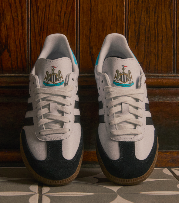 Close-up van Adidas Samba Newcastle United met gestikte overlays, gouden Samba-lettering en zwart-wit leren panelen JQ4044