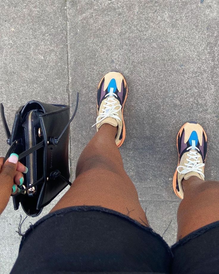 Adidas Yeezy 700 Wash Orange GW0296 gedragen met shorts en fiets, waarbij de chunky oranje zool en het retro silhouet duidelijk opvallen