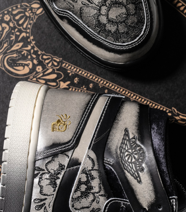 Close-up van de hiel met gouden embroidery en gegraveerde motieven op het bovenwerk – visuele hommage aan Día De Muertos-tradities in een modern silhouet