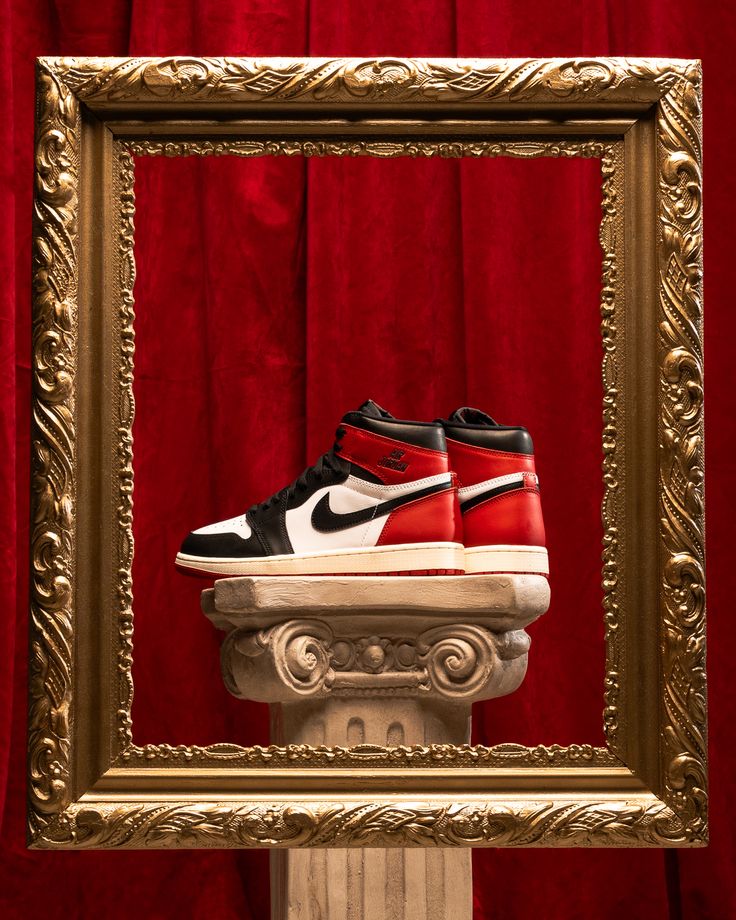 Air Jordan 1 Black Toe Reimagined in een gouden frame tegen rode achtergrond – collector style presentatie van deze OG high-top retro