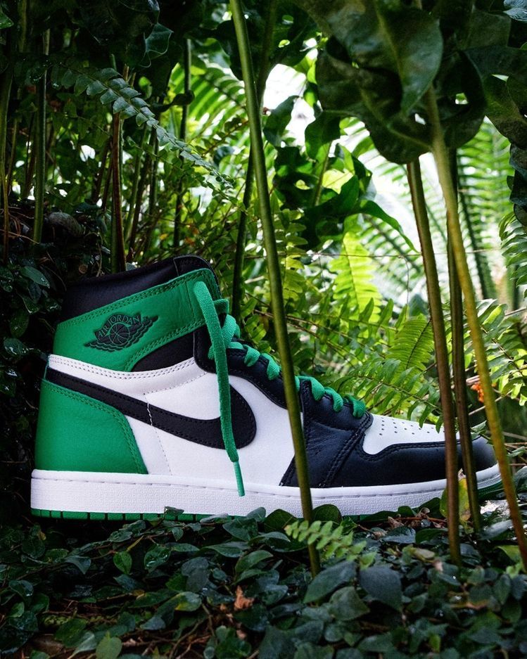 Flatlay van de sneaker naast de klassieke zwart-rode Nike-doos – retro Air Jordan 1 vibe met frisse kleuren