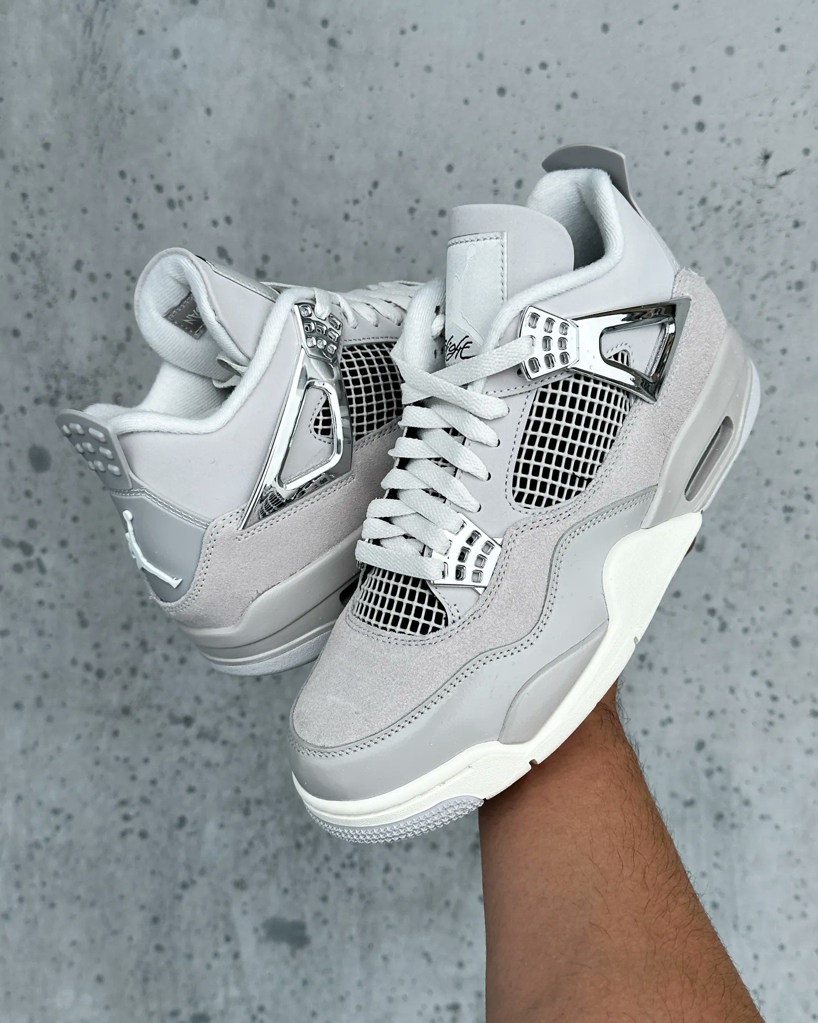 Close-up van de sneaker in hand, duidelijk zichtbare zilveren eyelets, nubuck materiaal en Air-unit in de zool.