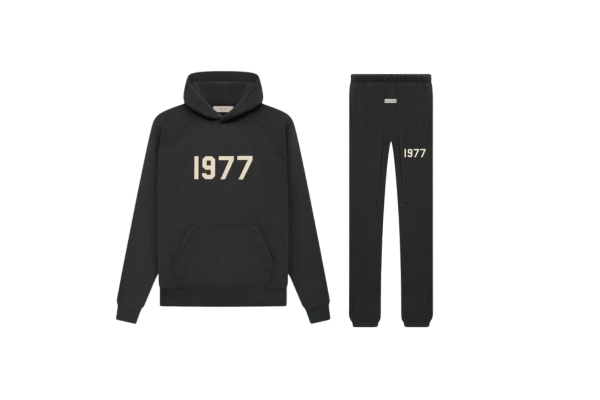 Studiofoto van de Fear of God Essentials IRON 1977 Full Set bestaande uit hoodie en sweatpants in zwarte kleur met 1977 opdruk