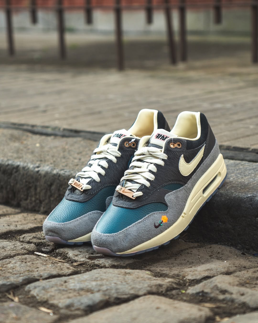 In hand shot van de Air Max 1 Kasina Grey met zicht op geperforeerd leer, touwachtige veters en gestikt Won-Ang logo – premium feel in elke afwerking