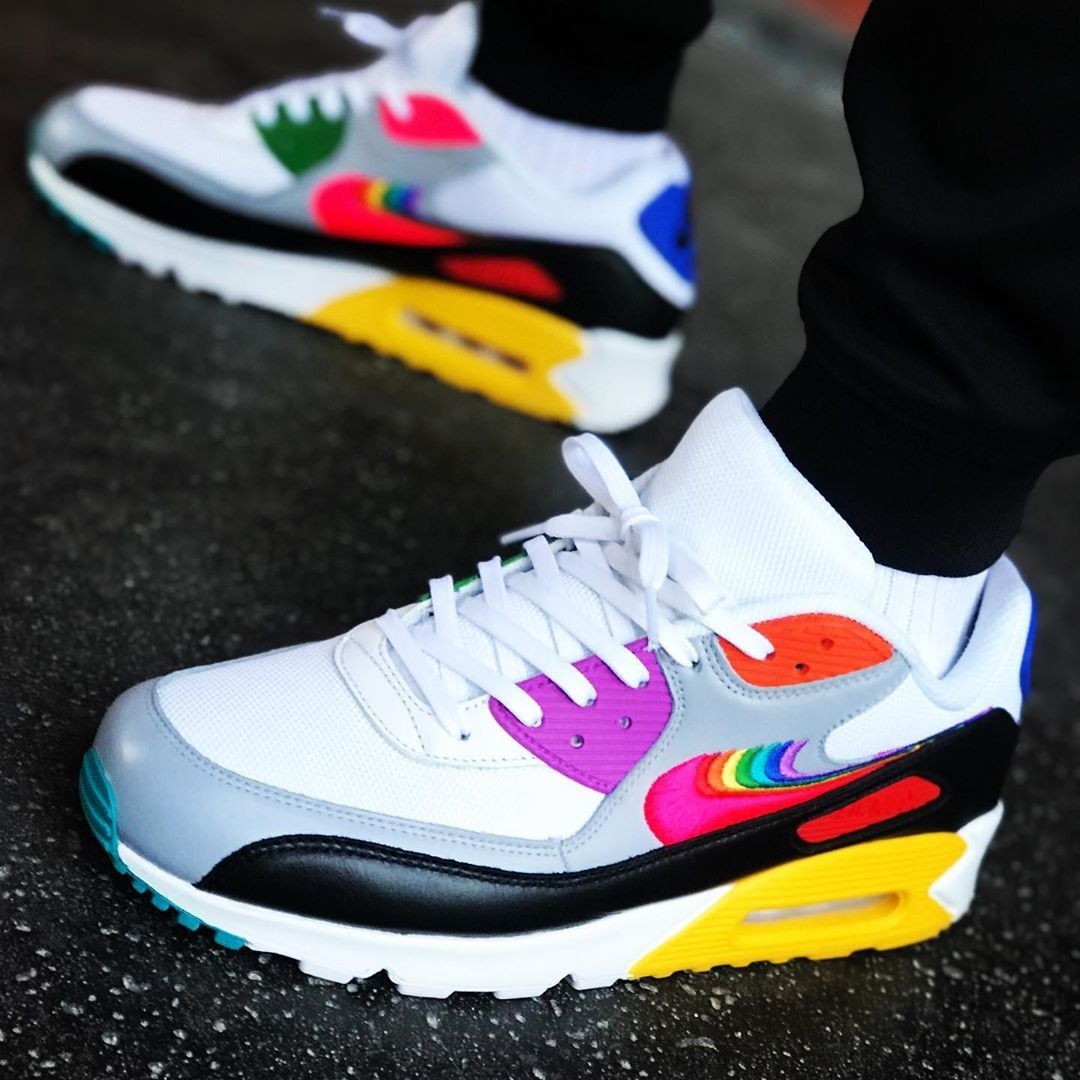 Flatlay van de Be True sneaker met OG-doos en regenboog-details – kleurrijke presentatie van een inclusieve en limited Air Max 90