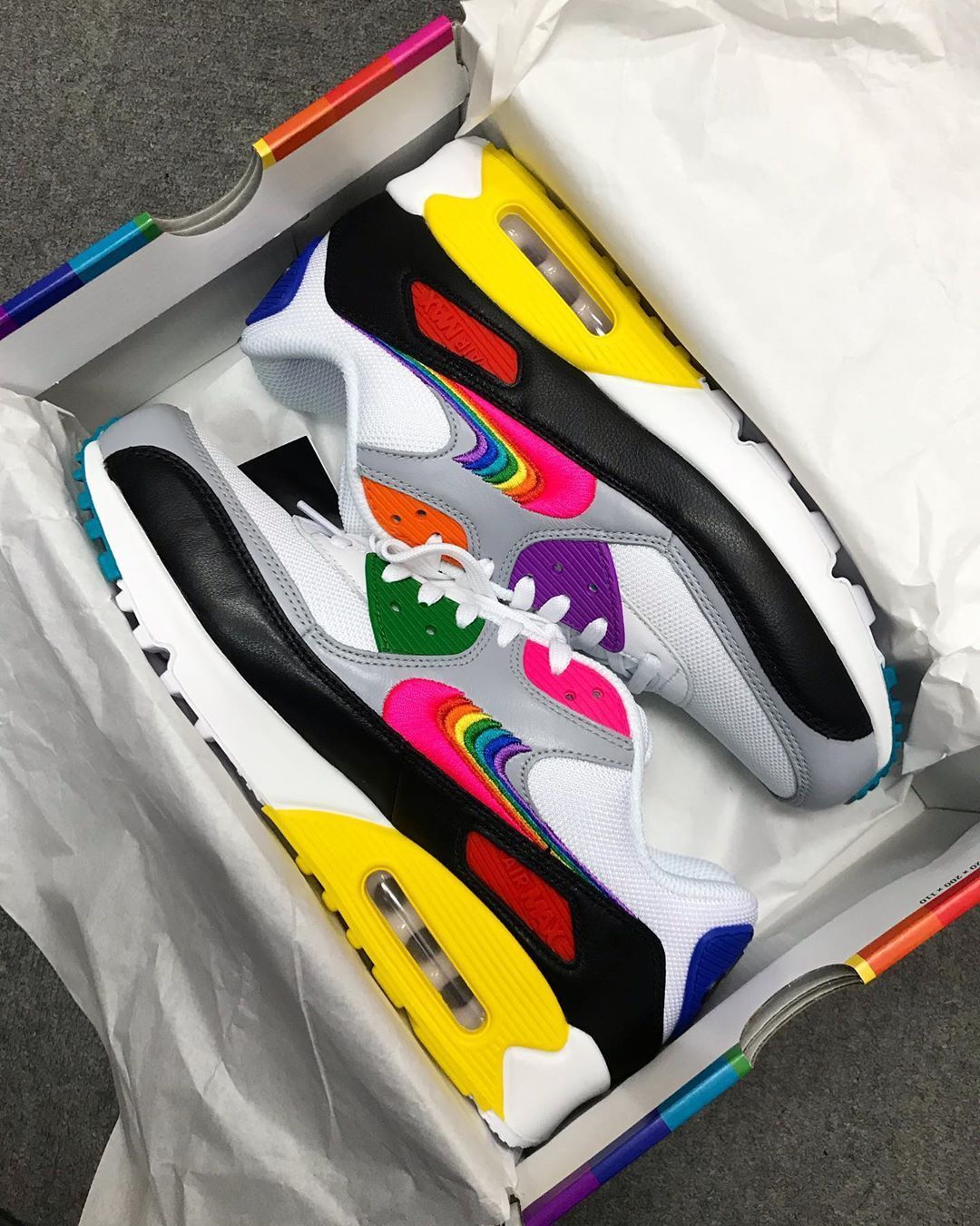 Hielaanzicht van de Air Max 90 Be True met zicht op roze accent, transparante hielstructuur en Nike Air logo in rainbow stijl