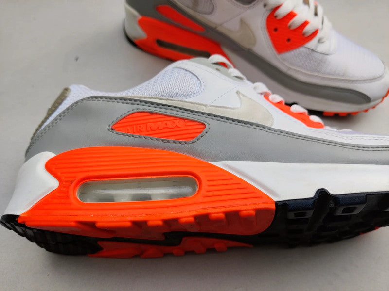 Flatlay van de sneaker naast OG-doos – witte, grijze en oranje tinten komen samen in een energieke en draagbare presentatie