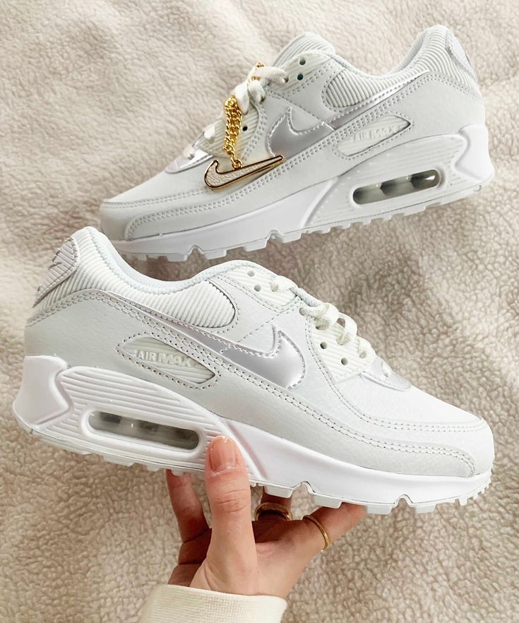 In hand shot van de sneaker met zicht op glanzend wit leer, de Lucky Charms ketting en zichtbare Air-unit – elegant en licht van karakter