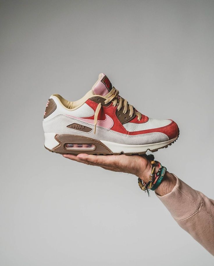 Achteraanzicht van de sneaker met zicht op beige hielstructuur, geborduurd Nike-logo en subtiele roze details