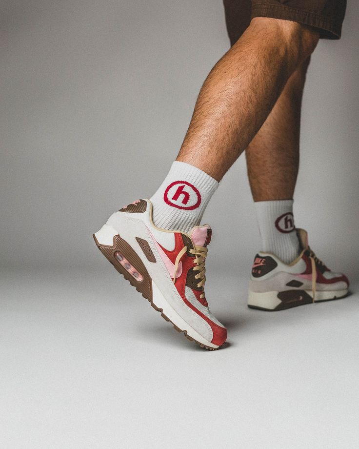 In hand shot van de sneaker met zicht op rood suède, roze veters en zichtbare Air-unit – rijke materialen en nostalgisch kleurenschema