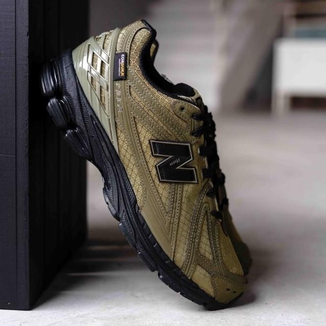In-hand view van de New Balance 1906R in Camo Olive. De combinatie van outdoor-stijl en performance-DNA maakt dit een opvallende en functionele release binnen de 1906R-serie.
