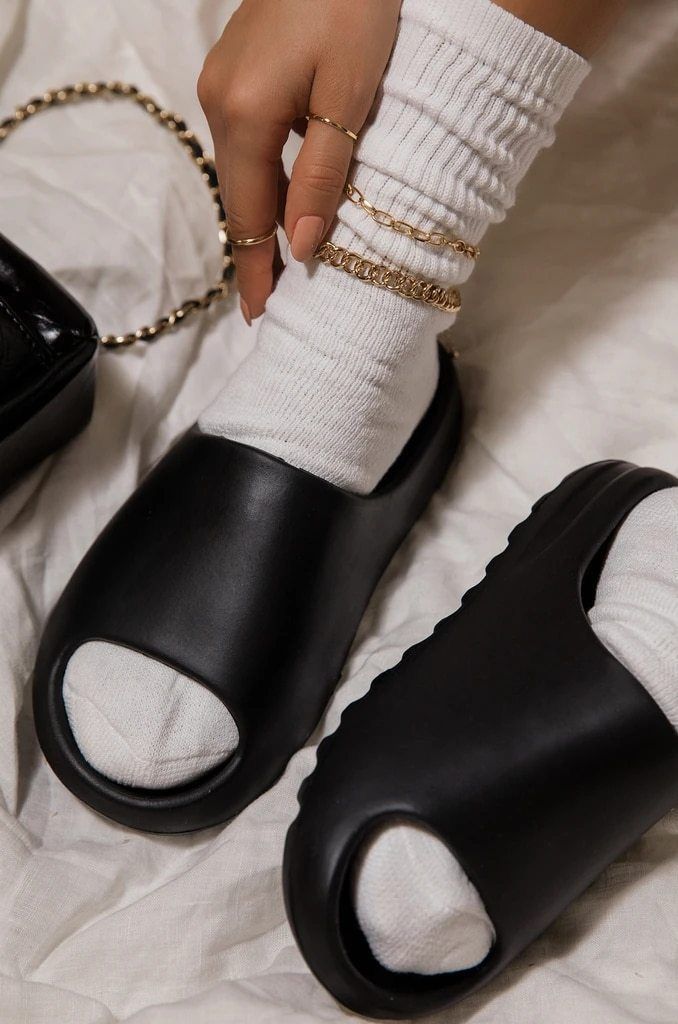 In-hand shot van Yeezy Slide Granite ID4134 – donkergrijze EVA body, diepe ribbelzool en minimal design in daglicht