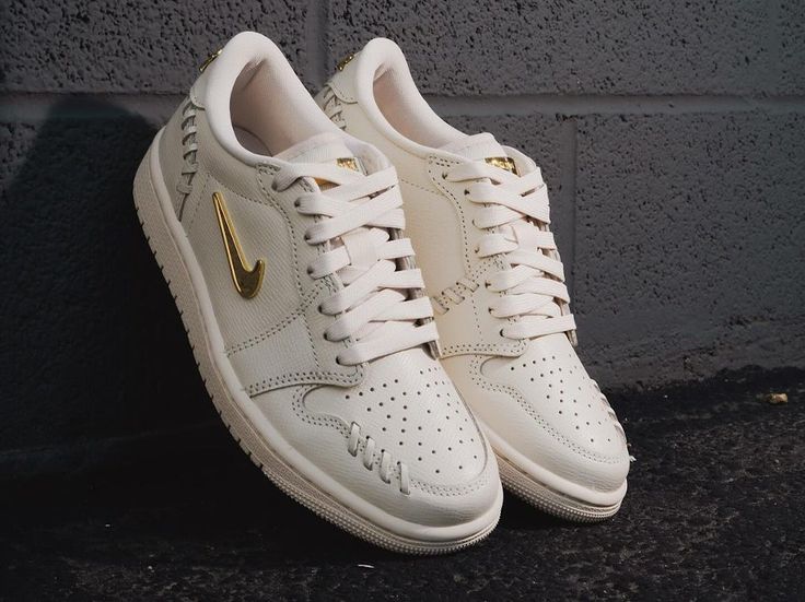 Air Jordan 1 Low Method of Make Legend Light Brown (SKU FN5032-200) – in-hand shot met zicht op metallic gold Wings-logo en leertextuur