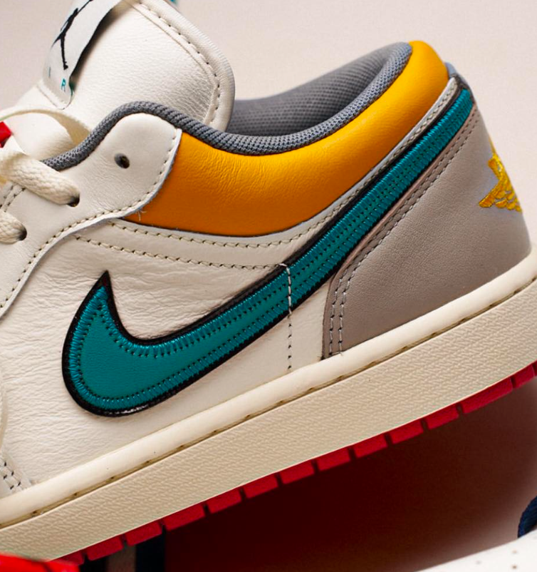 Air Jordan 1 Retro Low PRM Sail Cashmere (SKU HV4511‑133) – in‑hand shot met zicht op premium leather, teal/yellow Wings‑logo en lace toggle