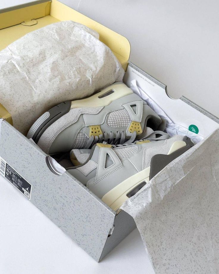 Air Jordan 4 Craft Photon Dust DV3742-021 in hand vastgehouden met zicht op geribbelde hielclip, zachte overlays en grijze ton-sur-ton afwerking