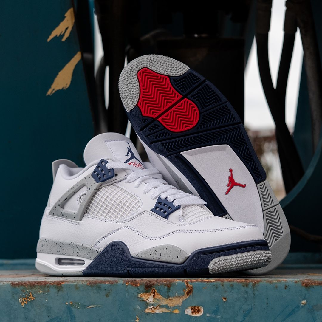 Close-up van DH6927-140 toont het Jumpman-logo op de tong, cementaccenten rond de zool en diep navy cages tegen wit leer
