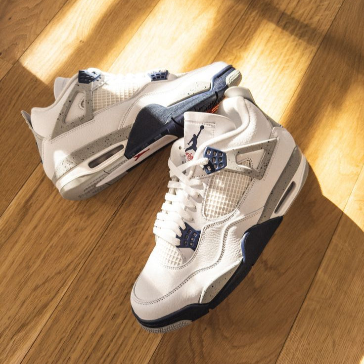 Originele verpakking van DH6927-140 opengeklapt met beide sneakers schuin gepositioneerd op cementdoospapier, navy details in focus