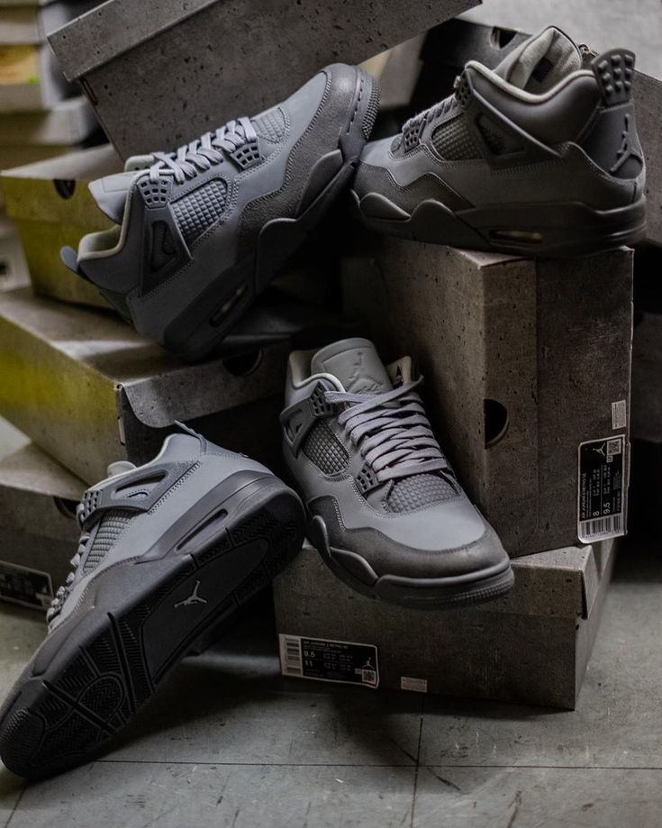 Air Jordan 4 Wet Cement FQ7928-001 in hand vastgehouden met zicht op translucent zool, glanzend hielstuk en suède overlays in zacht licht