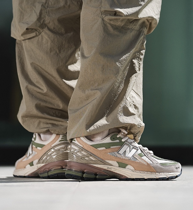 In-hand view van de New Balance M1906NE in Linen en Dark Olivine. De combinatie van zachte tinten en performance-elementen maakt dit model tot een opvallende release binnen de 1906-serie.