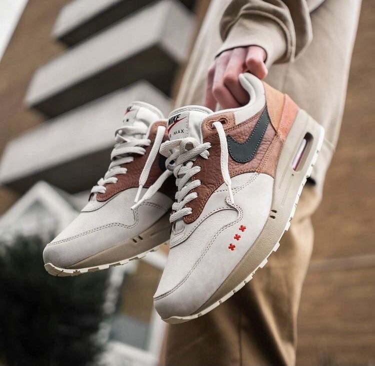 Lifestyle close-up met beide sneakers gedragen in een stedelijke setting, waarbij de aardse kleuren harmoniëren met het lijnenspel van de achtergrond