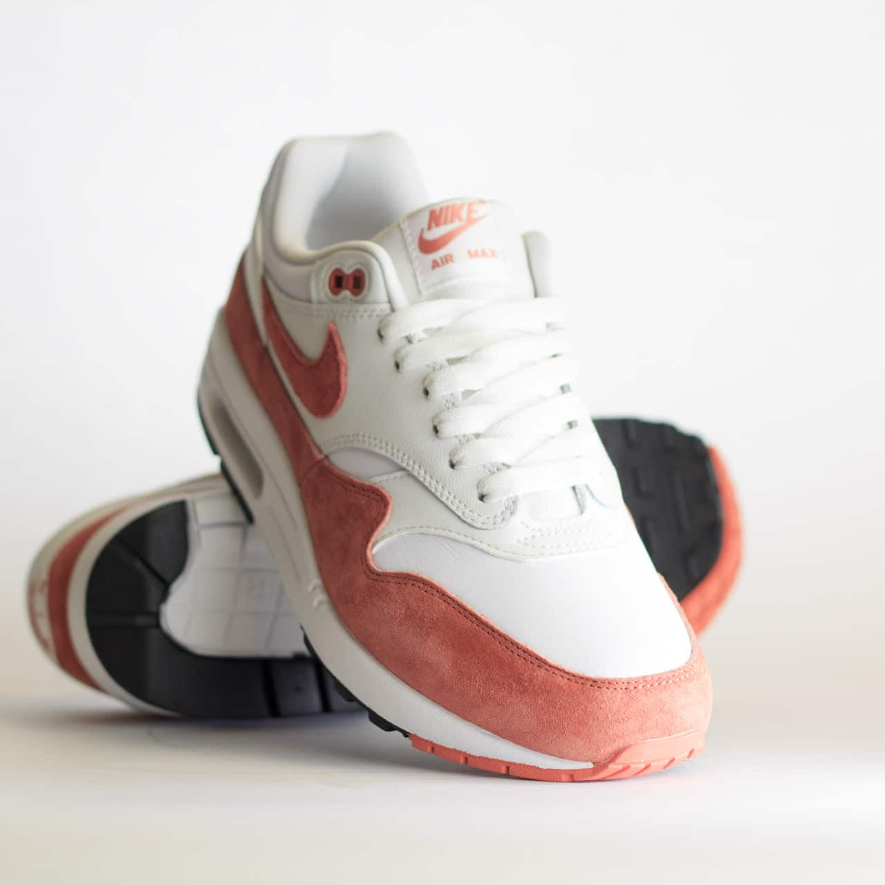 Sneaker balancerend op de hiel met zicht op de gebogen zoolvorm, roze suède en minimalistisch veterwerk