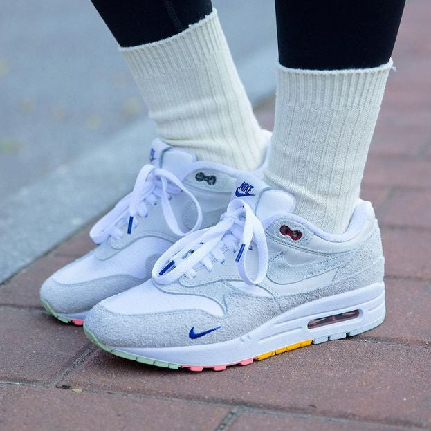 On feet shot met witte sokken, zichtbaar profiel van de buitenzool en geborduurde mini Swoosh op de toebox