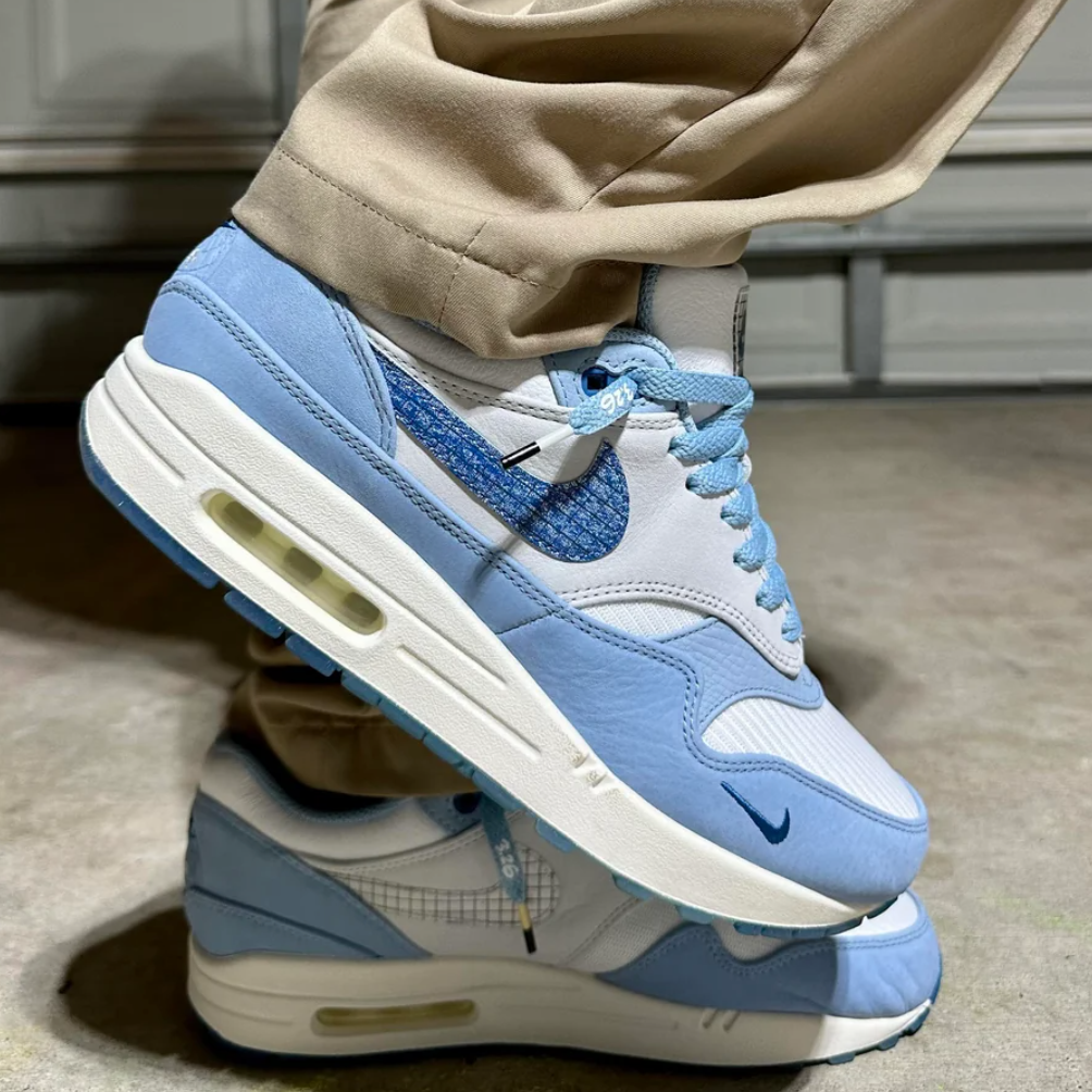 Gestapelde sneakershot van de Nike Air Max 1 Blueprint, zicht op translucent outsole en layering van wit leer en blauw suède
