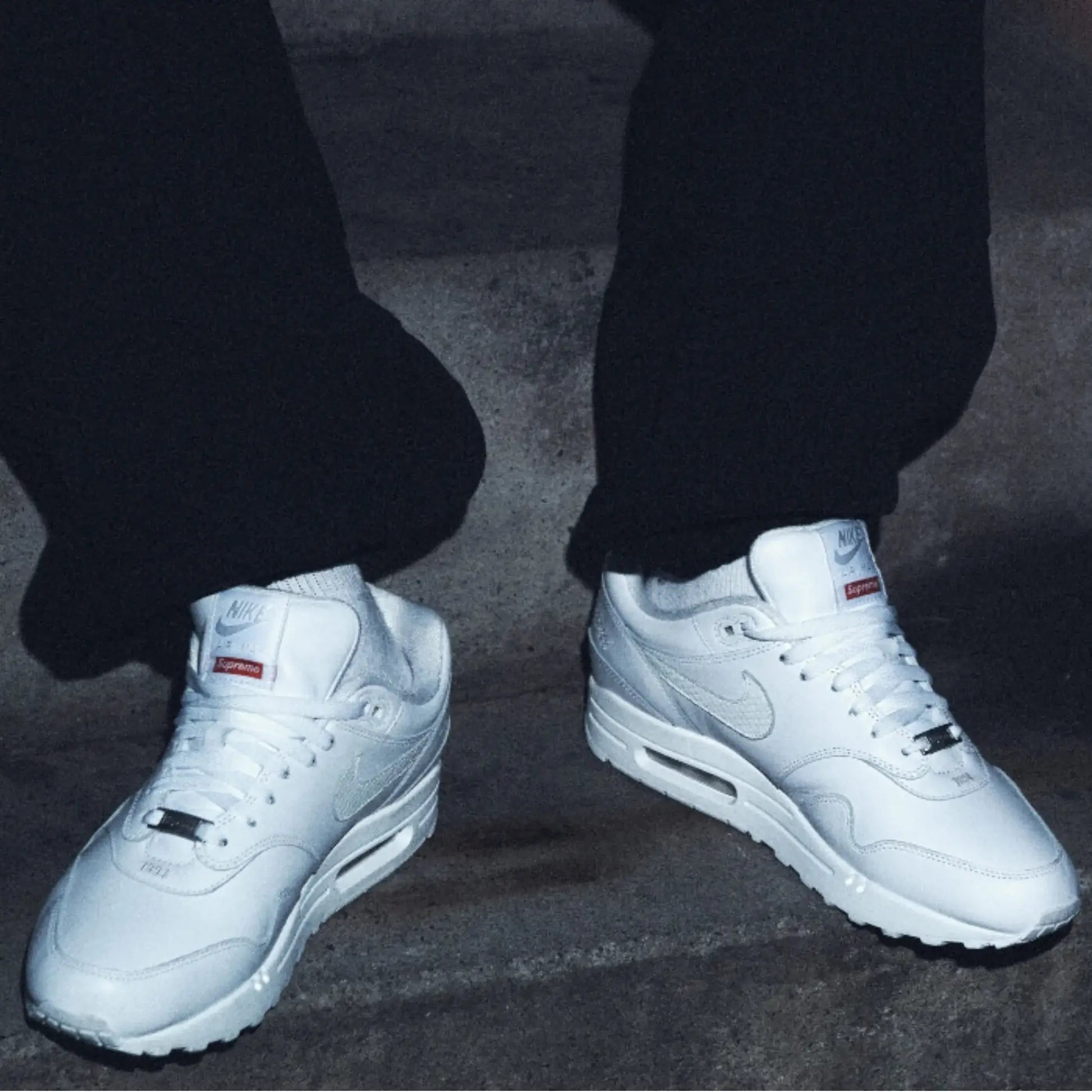 In-hand shot van Nike Air Max 1 Supreme Triple White DV7796-100 – premium witte upper, zachte lining en Air Max zool met transparant venster