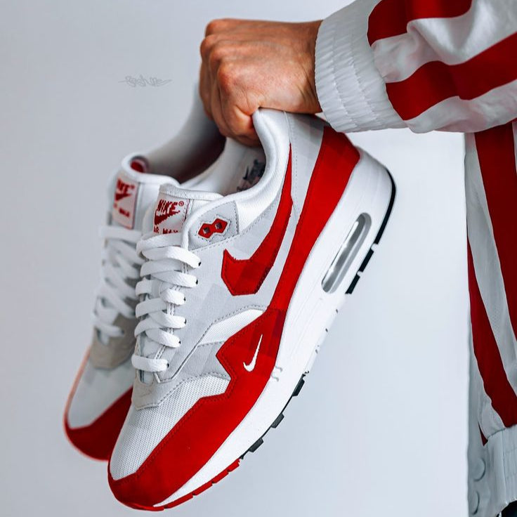 On-feet shot met rood-wit gestreepte broek, waarin de kleurblokken en het lage silhouet van de AM1 perfect tot z’n recht komen