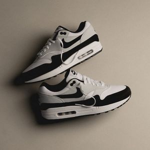 Twee sneakers geflatlayd tegen een beige achtergrond met zachte schaduwen, wat het minimalistische design versterkt