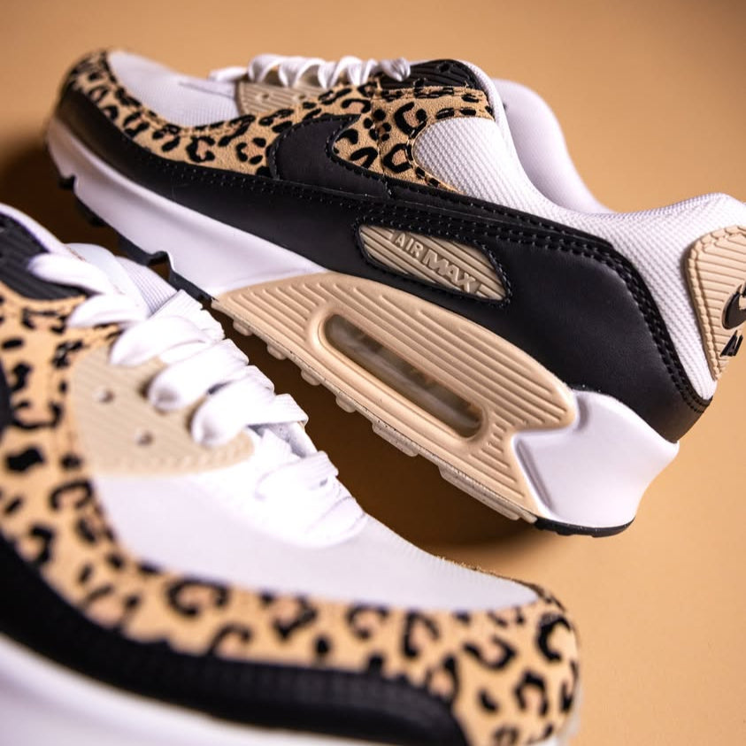 Close-up van de Air Max 90 IF1619-100 met focus op de animal print en beige Air-unit, scherp in beeld op warme achtergrond