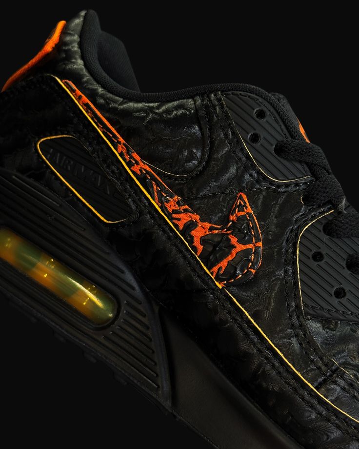 In hand shot van de Nike AM90 QS Volcano met ruwe suède afwerking, zwarte Swoosh en contrasterende gele highlights