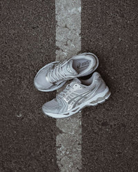 Bovenaanzicht van de sneaker met focus op grijze veters, reflecterende panelen en dynamische lijnen – iconisch Kayano-silhouet

