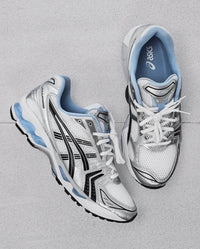 Bovenaanzicht van de sneaker met wit mesh, zilveren overlays, blauwe details en subtiel JJJJound-logo op de tong

