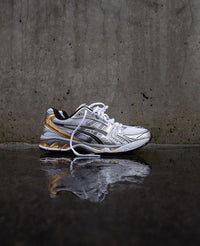 ASICS Gel Kayano 14 White Pure Gold vastgehouden in daglicht met zicht op reflecterende mesh en gouden details – SKU 1202A056 112


