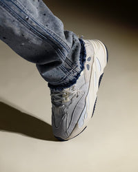 Adidas Yeezy 700 Analog EG7596 on feet gecombineerd met blauwe denim jeans, waarbij de monochrome stijl van de sneaker goed naar voren komt
