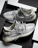 Adidas Yeezy Boost 350 V2 Static EF2905 als paar gefotografeerd op een zwart-wit achtergrond, waarbij de doorschijnende strepen goed uitkomen