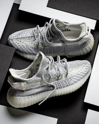 Adidas Yeezy Boost 350 V2 Static EF2905 als paar gefotografeerd op een zwart-wit achtergrond, waarbij de doorschijnende strepen goed uitkomen