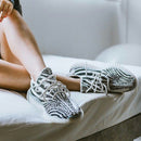 Adidas Yeezy Boost 350 V2 Zebra CP9654 gedragen binnenshuis op een witte bank, met focus op de zwart-witte colorway en knit details