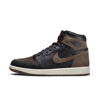 Zijkant van de Air Jordan 1 Palomino met zwart leer, bruine suède overlays en gouden Nike Air tongue label – krachtige retro uitstraling met luxe feel

