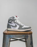 Flatlay van de sneaker en OG-box – de mix van grijs, wit en sail zorgt voor een subtiele maar sterke retro-uitstraling

