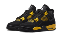 Close-up van de Air Jordan 4 Thunder met zwarte upper, gele veterhouders en stevige zwarte zool met contrastdetails.