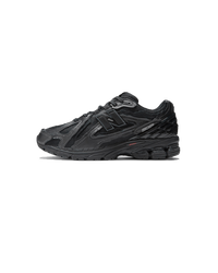 New Balance 1906D Protection Pack Black Leather zijaanzicht met glanzende leren overlays en gerafelde details

