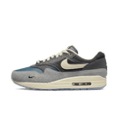 Zijkant van de Nike Air Max 1 Kasina Grey met premium suède, pony hair en zilveren mini Swoosh – Koreaanse collab met diepe materialenmix