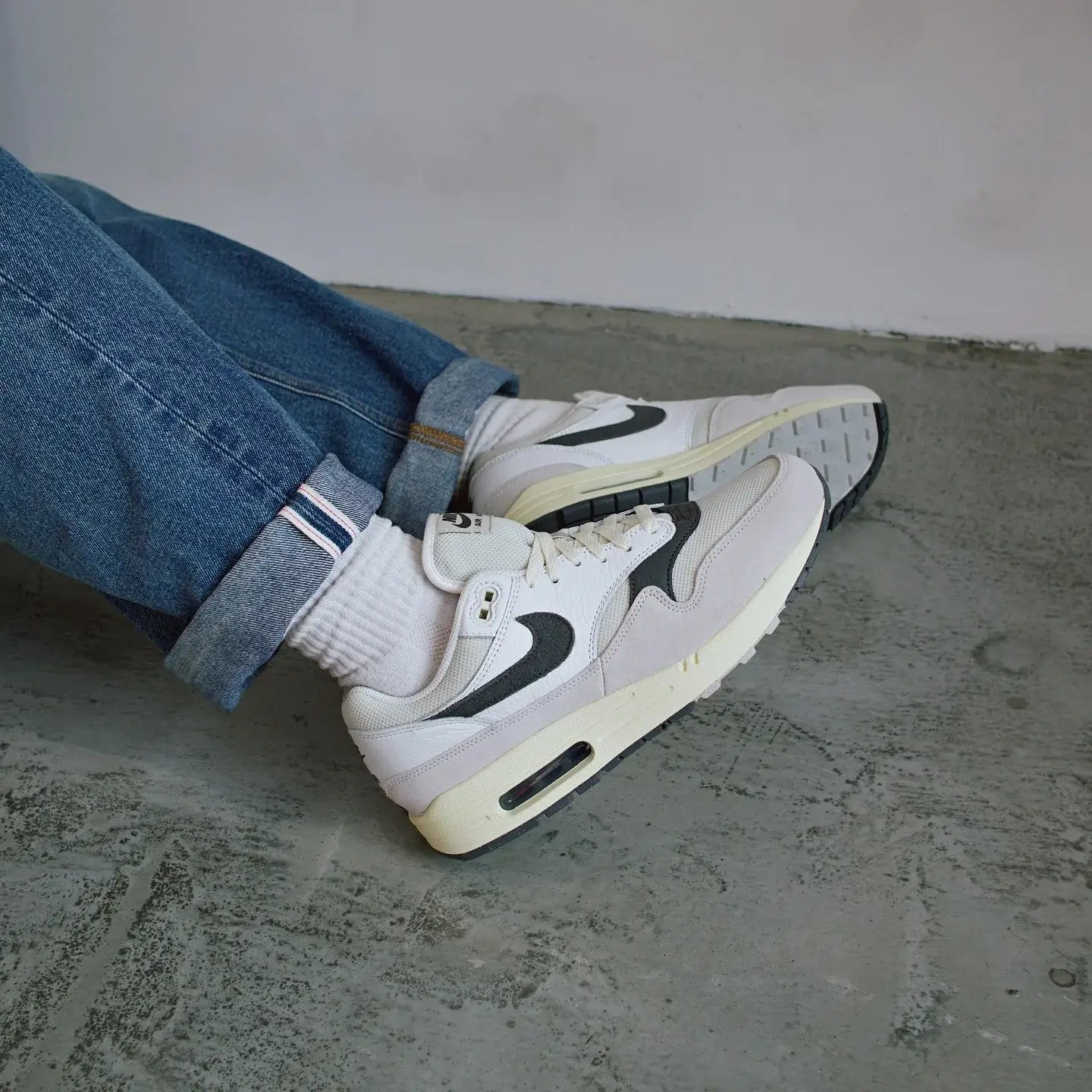 In hand shot van de sneaker met close-up op de suède afwerking, mesh toebox en donkergrijze Swoosh – premium materialen en textuurcontrast

