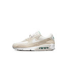 Zijkant van de Nike Air Max 90 First Use Cream met off-white suède, zacht mesh en gouden Swoosh-outline – clean look met historisch branding detail