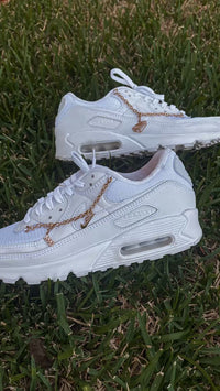 In hand shot van de sneaker met zicht op glanzend wit leer, de Lucky Charms ketting en zichtbare Air-unit – elegant en licht van karakter