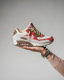 Achteraanzicht van de sneaker met zicht op beige hielstructuur, geborduurd Nike-logo en subtiele roze details
