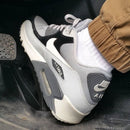 In hand shot van de sneaker met zicht op witte toebox, lichtgrijze mudguard en donkerblauwe Swoosh – mix van materialen in OG-vorm